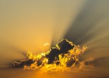 the sun behind a dark cloud light up the sky around