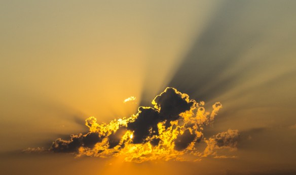 the sun behind a dark cloud light up the sky around